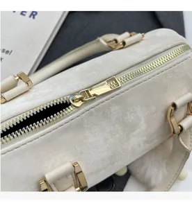 Détail de la fermeture éclair dorée et du cuir marbré sur un sac Boston blanc