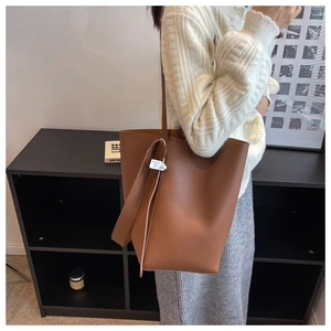 Side view of large brown lychee texture leather tote bag on model in modern interior