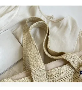 Détail des larges poignées tressées et de la texture paille beige du sac de plage