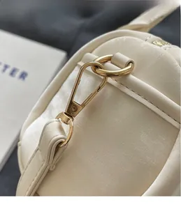 Gros plan détaillé du crochet en métal doré de qualité sur un sac boston blanc crème