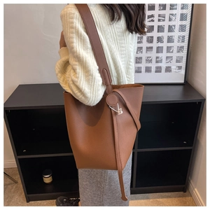 Brown litchi grain bucket bag detail showing the wide strap and retro texture