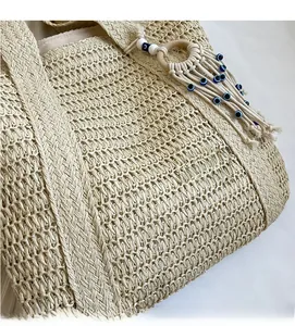 Gros plan du sac cabas en paille tissée avec breloque pompon œil bleu et texture détaillée