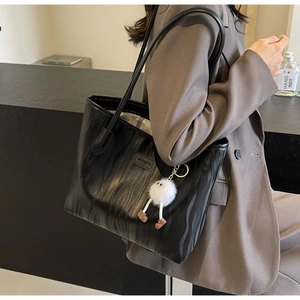 Close-up of black zebra embossed tote bag with brand label and plush charm detail