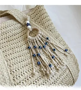Détail du sac cabas en paille avec glands en perles mauvais œil et anneaux en bois