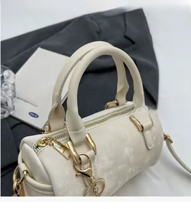 Détails du sac Boston avec fermeture dorée, pendentif coeur et texture en similicuir