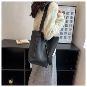 Detailed texture of black litchi grain leather on a large capacity bucket tote bag