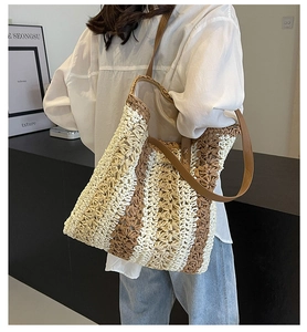 Detail der handgewebten Stroh-Tote-Bag mit zweifarbigen Streifen und Lederriemen am Model
