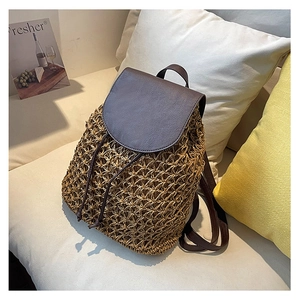 Detail of hand-woven straw texture and dark brown leather straps on a beach backpack