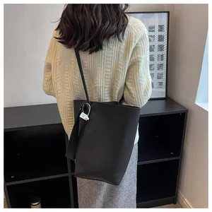 Detailed side view of a black pebbled leather bucket bag worn by a model in a minimalist room