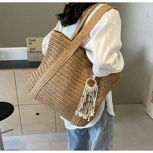 Détail du sac cabas en paille tissée avec pompon œil bleu et franges de style bohème