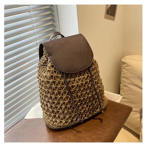 Detail view of woven straw backpack with premium dark brown leather flap and drawstring closure