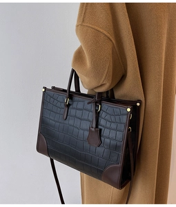 Detail view of the black crocodile pattern and brown leather patchwork on the tote bag
