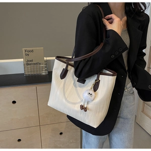 Chic cream tote bag with wave texture and brown straps shown on model in modern office