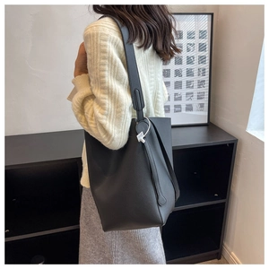 Detail showing the black lychee pattern leather bucket bag worn by a model on shoulder