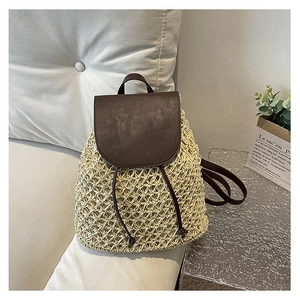 Detail of the woven straw backpack with dark brown leather flap and drawstring closure