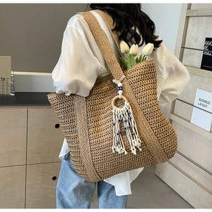 Gros plan détaillé d'un sac cabas en paille avec breloque œil bleu et décor de tulipe