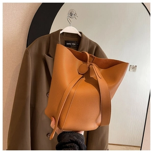 Close-up of deep camel litchi grain leather bucket bag with metallic ring detail