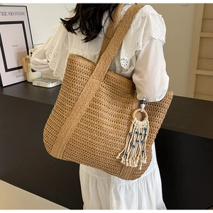 Détail du sac cabas en paille tressée avec pompon bohème et perles bleues de l'œil
