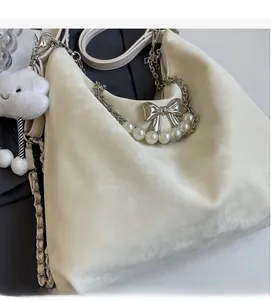 Detail der cremefarbenen Samt-Tasche mit Metallschleife, Perlen und Wolken-Anhänger