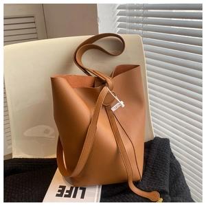 Close-up of brown litchi pattern leather bucket bag with shoulder strap and drawstring