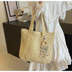 Sac cabas en paille tissée beige avec pompon œil maléfique dans un décor de café