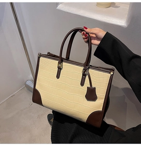 Detail of beige crocodile embossed leather tote bag with dark brown contrast stitching