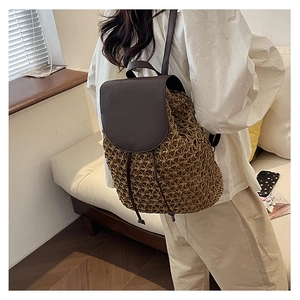 Detail of hand-woven straw backpack with brown leather straps shown on model back