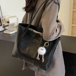 Large black textured faux leather tote bag with a plush doll charm for commuting