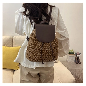 Rear view of a woven straw backpack with brown leather accents for beach vacation travel