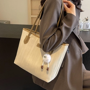 Minimalist beige water ripple tote bag with brown straps and plush ball charm