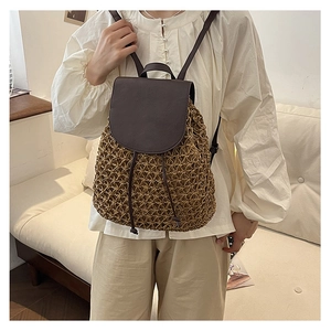 Detail of hand-woven straw backpack with brown leather flap and adjustable shoulder straps