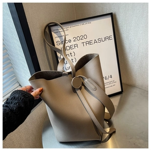 Detail of taupe pebbled leather bucket bag on a modern metallic surface