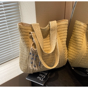 Gros plan détaillé d'un sac cabas en paille tissée avec franges bohèmes et charme œil