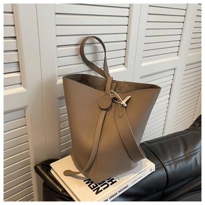 Detailed close-up of taupe litchi grain leather bucket bag with circular hardware