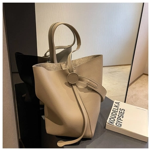 Detailed macro view of the lychee grain leather texture and round leather buckle of the tote