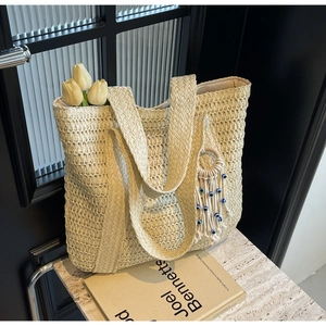Gros plan détaillé du sac cabas en paille avec pompon œil bleu et tulipes blanches