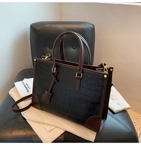Macro detail of black crocodile embossed leather texture with brown strap and gold metal hardware