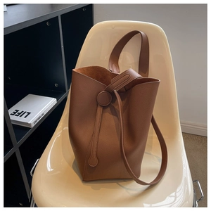 Detailed macro view of caramel lychee leather texture and suede interior on bucket bag