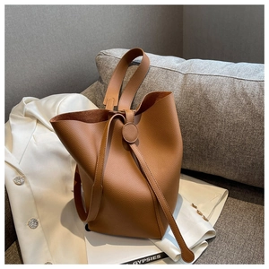 Brown litchi grain leather bucket bag with unique round leather drawstring on sofa