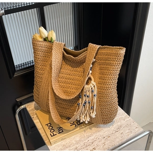 Détail du sac cabas en paille tressée avec pompon décoratif et perle œil grec