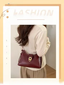 Detail of burgundy leather bucket bag with elegant golden oval metal lock and smooth finish