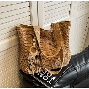 Détail d'un sac cabas en paille marron tressé main avec pendentif œil et large bandoulière