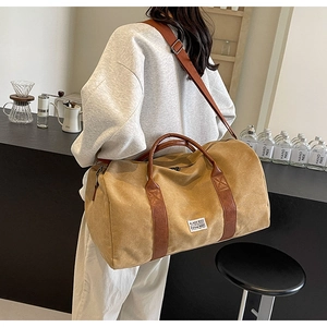 Sac de voyage en toile kaki avec anses en cuir marron porté par un mannequin en café