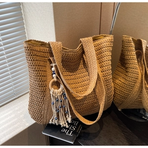 Détail du sac cabas en paille tressée avec pompon œil bleu et texture naturelle
