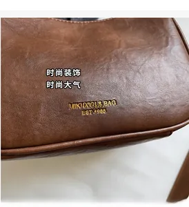 Close-up of brown leather bag showing gold brand lettering and fine material texture