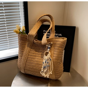 Gros plan détaillé sur la texture du sac en paille et le gland à perles bohème