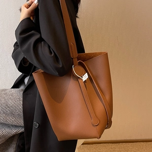 Brown lychee leather bucket bag with wide shoulder strap for minimalist commute style