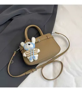 Detail of khaki pebbled leather bucket bag with silver hardware and cute plush charm