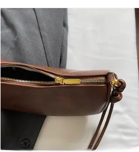 Close-up of smooth gold metal zipper and lychee texture on brown leather handbag
