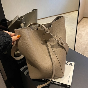 Chic elephant gray pebble leather bucket bag with circular clasp for minimalist daily commute
